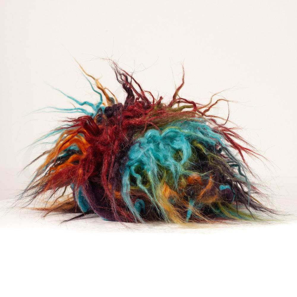 Slightly angled back view of a cuttlepod plush toy, highlighting two-tone ruffled fins, and a cuddly, furry body that comes to a soft point at the rear.