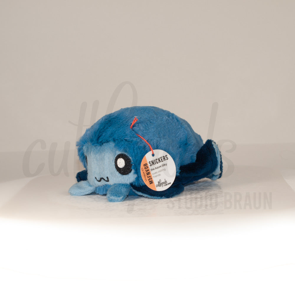 Front view of a cuttlepod plush toy, captured at a slight angle to highlight its charming features: large, cartoonish eyes, ruffled fins, and a cuddly, furry texture.