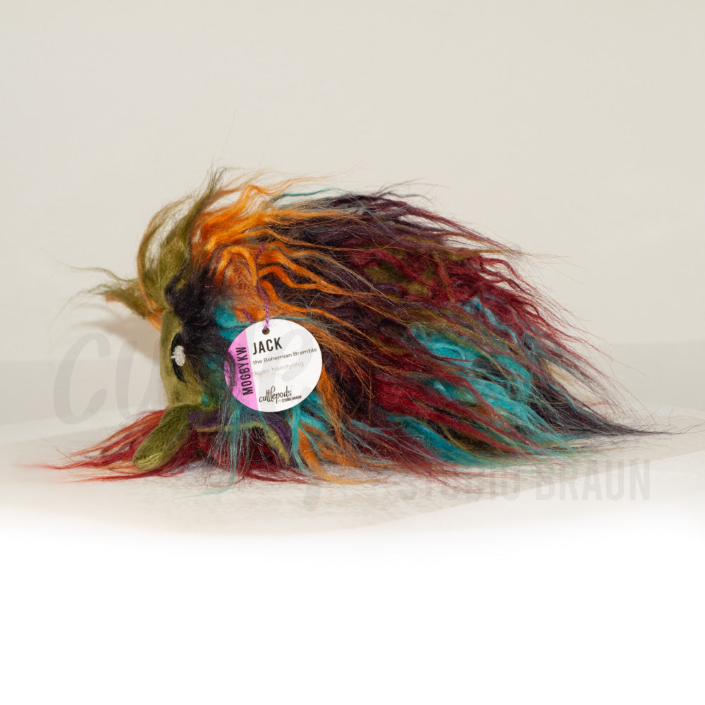 Side profile view of a cuttlepod plush toy, showcasing two-tone ruffled fins, and a cuddly, furry body.