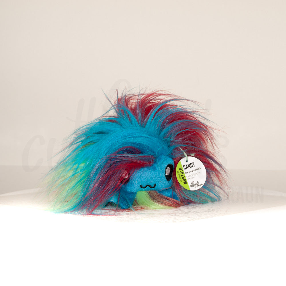 Front view of a cuttlepod plush toy, showcasing its unique form with large, cartoonish eyes, ruffled fins, and a cuddly, furry texture.