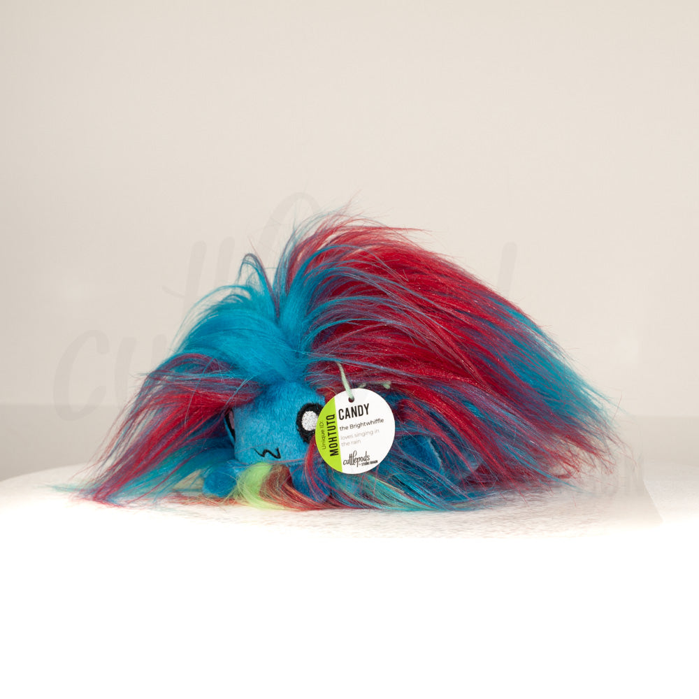 Front view of a cuttlepod plush toy, captured at a slight angle to highlight its charming features: large, cartoonish eyes, ruffled fins, and a cuddly, furry texture.