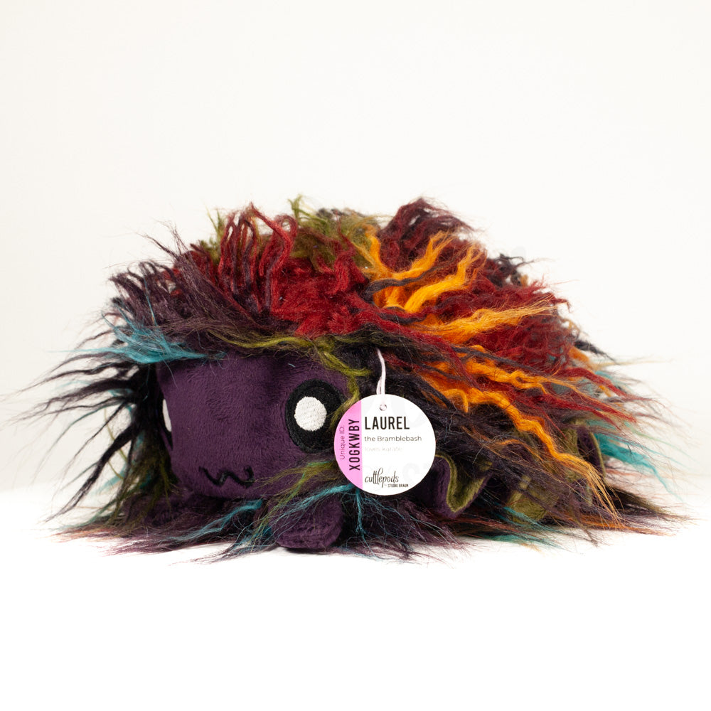 Front view of a cuttlepod plush toy, captured at a slight angle to highlight its charming features: large, cartoonish eyes, ruffled fins, and a cuddly, furry texture.