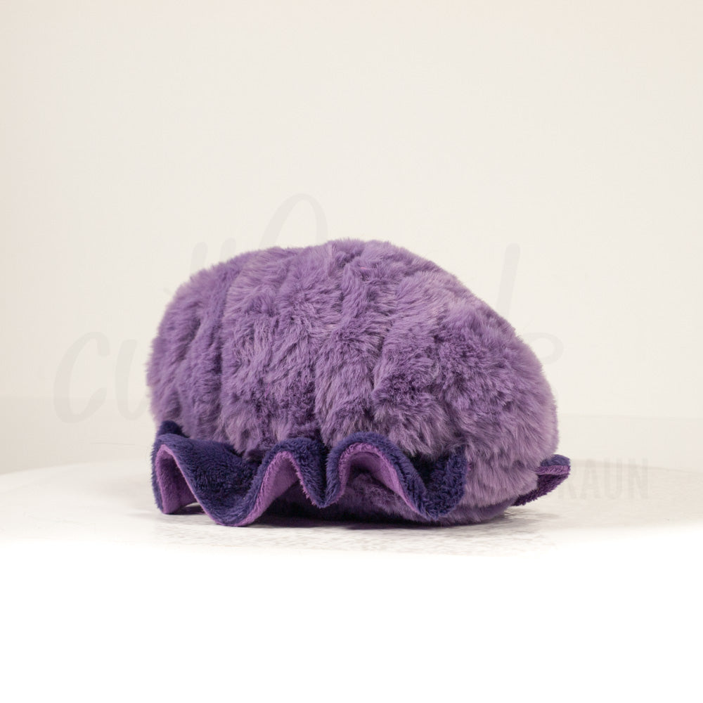 Slightly angled back view of a cuttlepod plush toy, highlighting two-tone ruffled fins, and a cuddly, furry body that comes to a soft point at the rear.