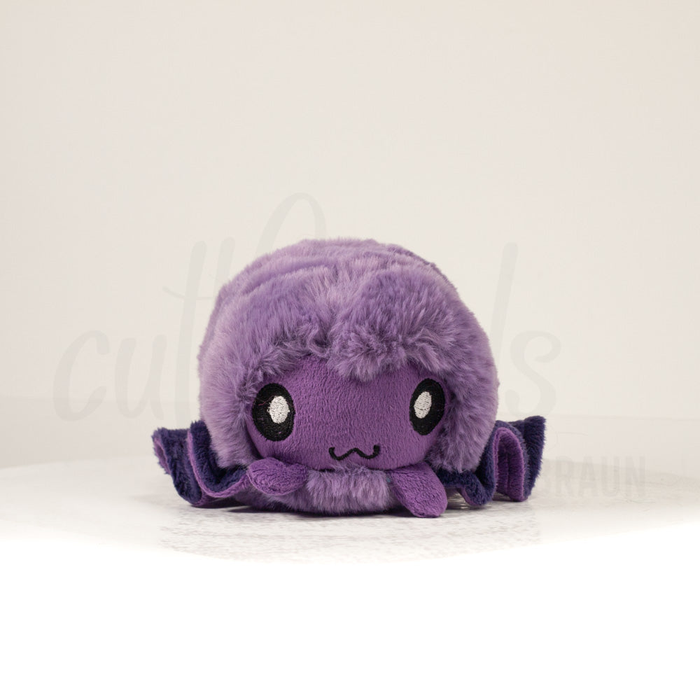 Front view of a cuttlepod plush toy, showcasing its unique form with large, cartoonish eyes, ruffled fins, and a cuddly, furry texture.