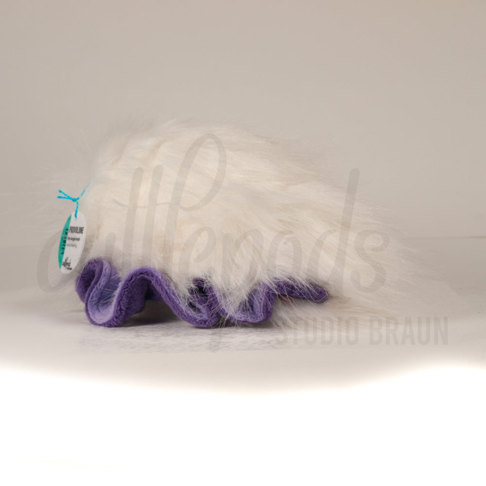 Slightly angled back view of a cuttlepod plush toy, highlighting two-tone ruffled fins, and a cuddly, furry body that comes to a soft point at the rear.