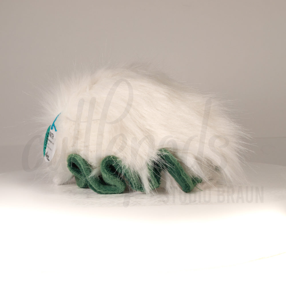 Slightly angled back view of a cuttlepod plush toy, highlighting two-tone ruffled fins, and a cuddly, furry body that comes to a soft point at the rear.