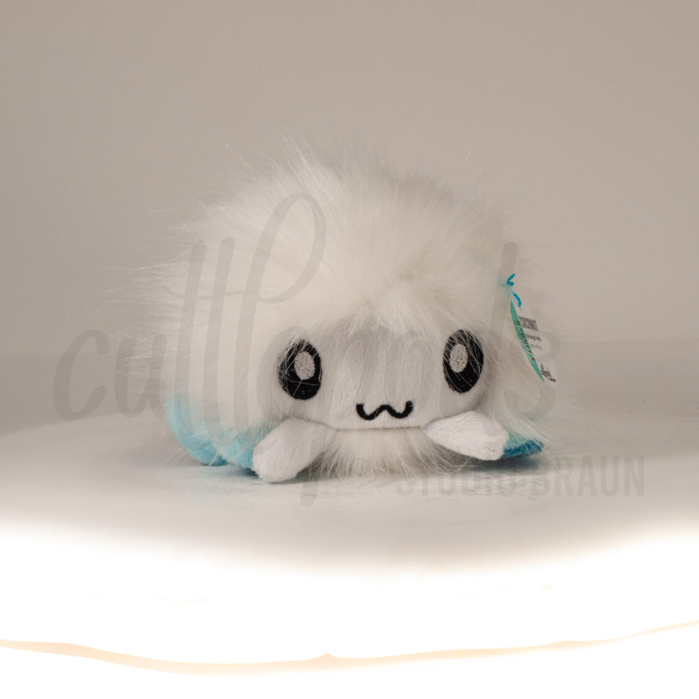 Front view of a cuttlepod plush toy, showcasing its unique form with large, cartoonish eyes, ruffled fins, and a cuddly, furry texture.