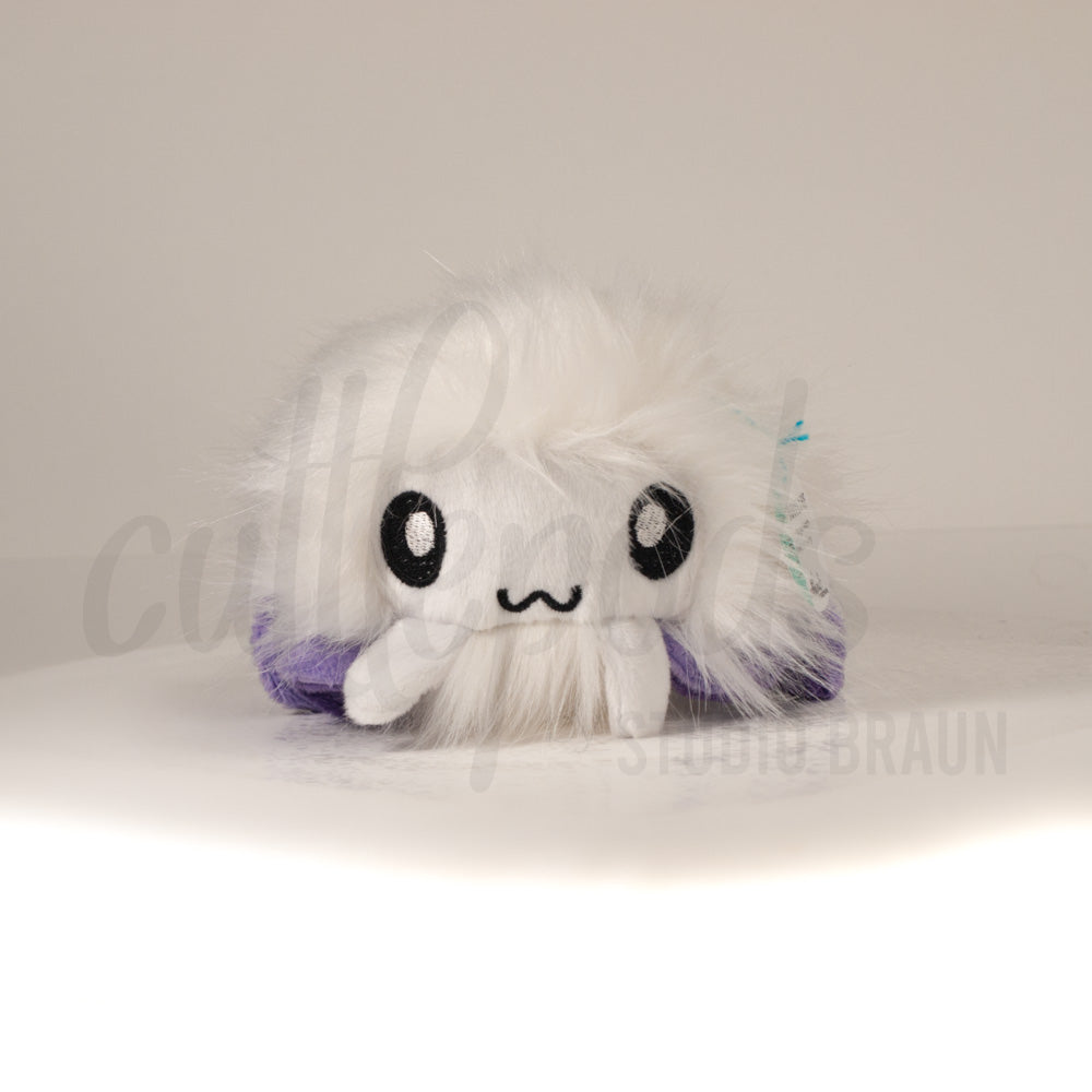 Front view of a cuttlepod plush toy, showcasing its unique form with large, cartoonish eyes, ruffled fins, and a cuddly, furry texture.