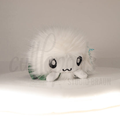 Front view of a cuttlepod plush toy, showcasing its unique form with large, cartoonish eyes, ruffled fins, and a cuddly, furry texture.