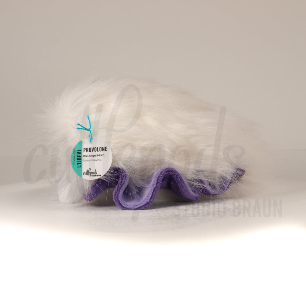 Side profile view of a cuttlepod plush toy, showcasing two-tone ruffled fins, and a cuddly, furry body.