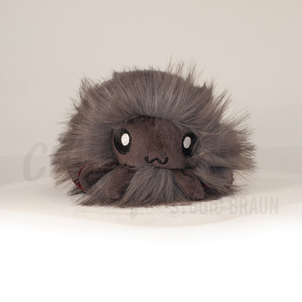 Front view of a cuttlepod plush toy, showcasing its unique form with large, cartoonish eyes, ruffled fins, and a cuddly, furry texture.