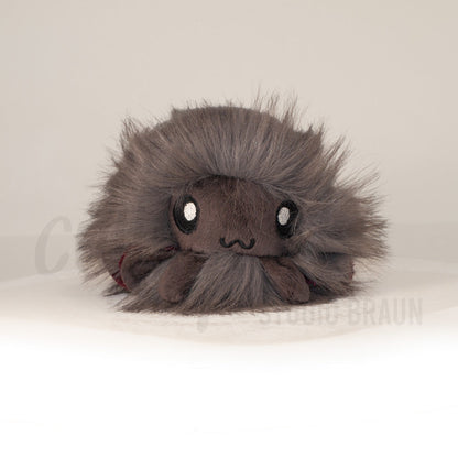 Front view of a cuttlepod plush toy, showcasing its unique form with large, cartoonish eyes, ruffled fins, and a cuddly, furry texture.