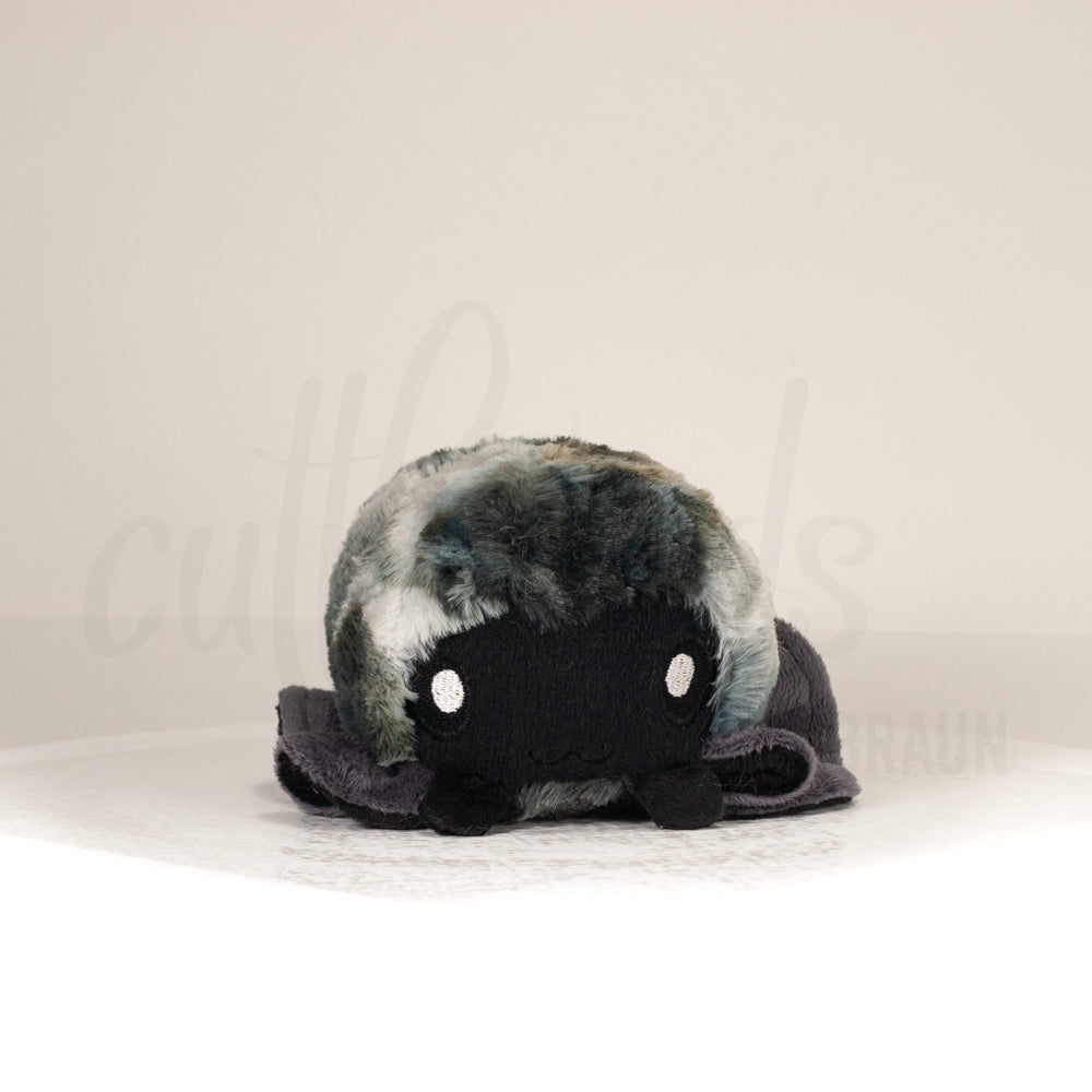 Front view of a cuttlepod plush toy, showcasing its unique form with large, cartoonish eyes, ruffled fins, and a cuddly, furry texture.