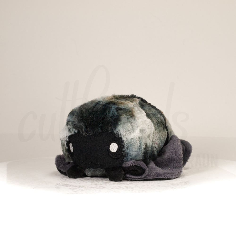 Front view of a cuttlepod plush toy, captured at a slight angle to highlight its charming features: large, cartoonish eyes, ruffled fins, and a cuddly, furry texture.