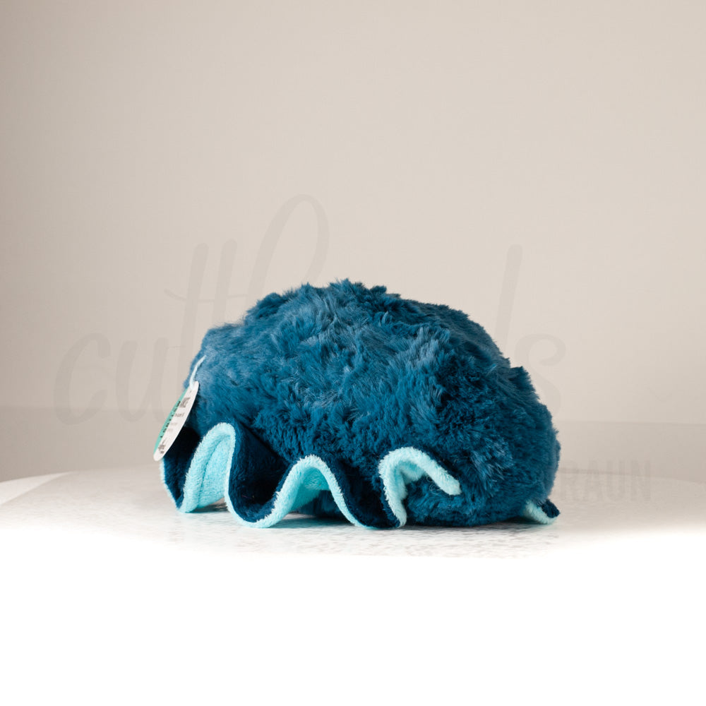 Slightly angled back view of a cuttlepod plush toy, highlighting two-tone ruffled fins, and a cuddly, furry body that comes to a soft point at the rear.