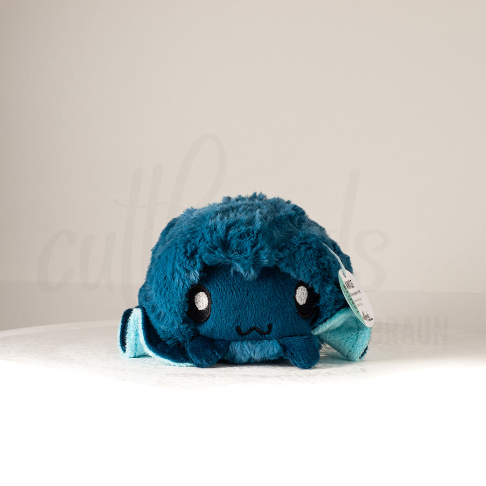 Front view of a cuttlepod plush toy, showcasing its unique form with large, cartoonish eyes, ruffled fins, and a cuddly, furry texture.