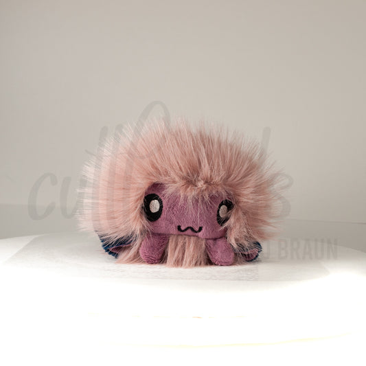 Front view of a cuttlepod plush toy, showcasing its unique form with large, cartoonish eyes, ruffled fins, and a cuddly, furry texture.