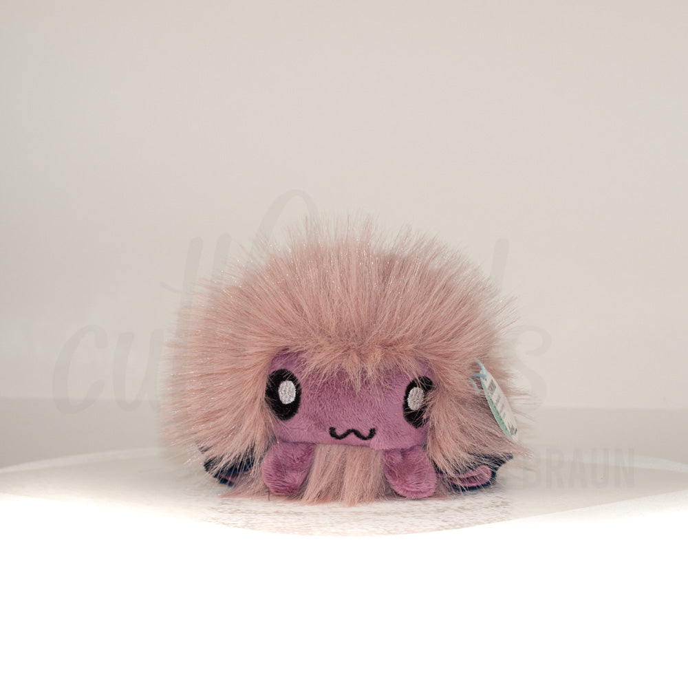 Front view of a cuttlepod plush toy, showcasing its unique form with large, cartoonish eyes, ruffled fins, and a cuddly, furry texture.