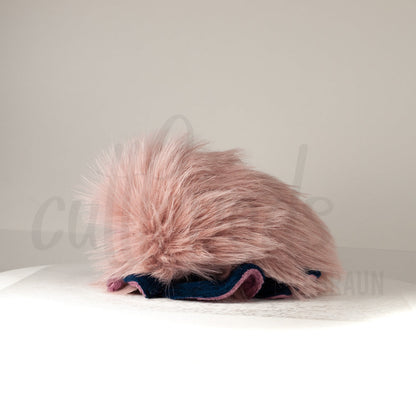 Side profile view of a cuttlepod plush toy, showcasing two-tone ruffled fins, and a cuddly, furry body.