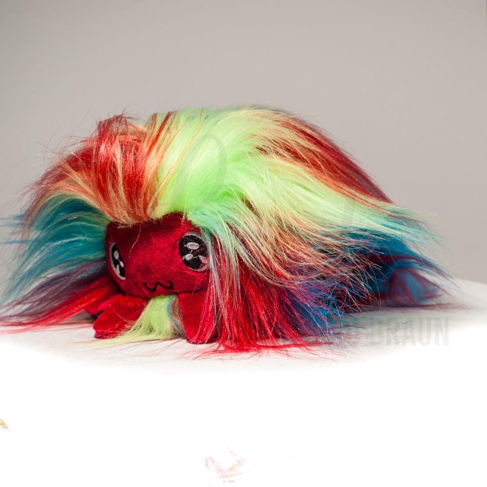 Front view of a cuttlepod plush toy, captured at a slight angle to highlight its charming features: large, cartoonish eyes, ruffled fins, and a cuddly, furry texture.