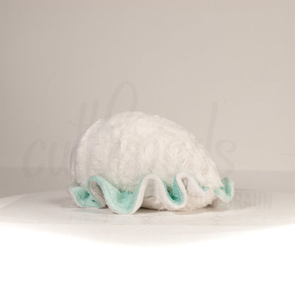 Slightly angled back view of a cuttlepod plush toy, highlighting two-tone ruffled fins, and a cuddly, furry body that comes to a soft point at the rear.