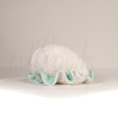 Slightly angled back view of a cuttlepod plush toy, highlighting two-tone ruffled fins, and a cuddly, furry body that comes to a soft point at the rear.