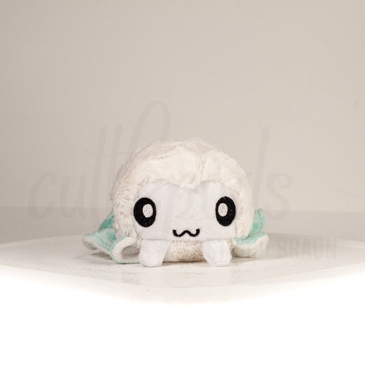 Front view of a cuttlepod plush toy, showcasing its unique form with large, cartoonish eyes, ruffled fins, and a cuddly, furry texture.