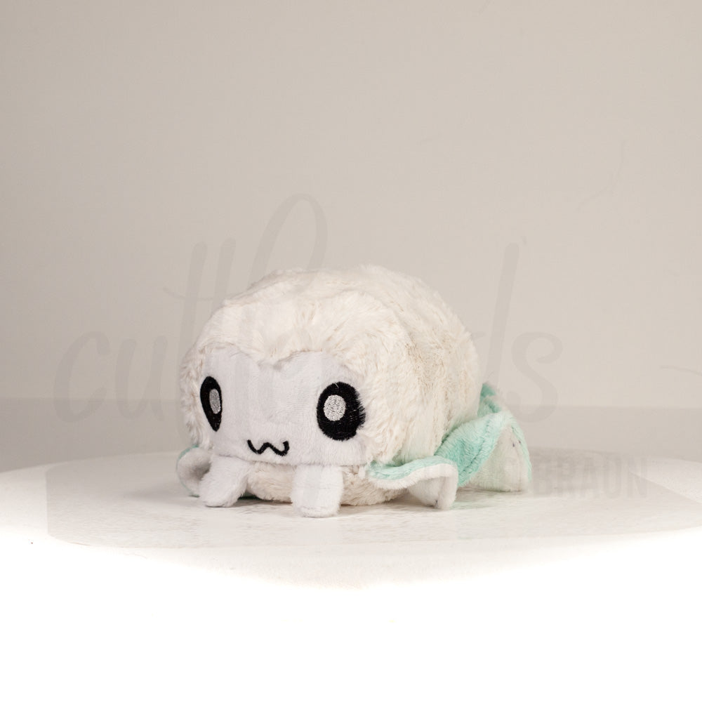 Front view of a cuttlepod plush toy, captured at a slight angle to highlight its charming features: large, cartoonish eyes, ruffled fins, and a cuddly, furry texture.