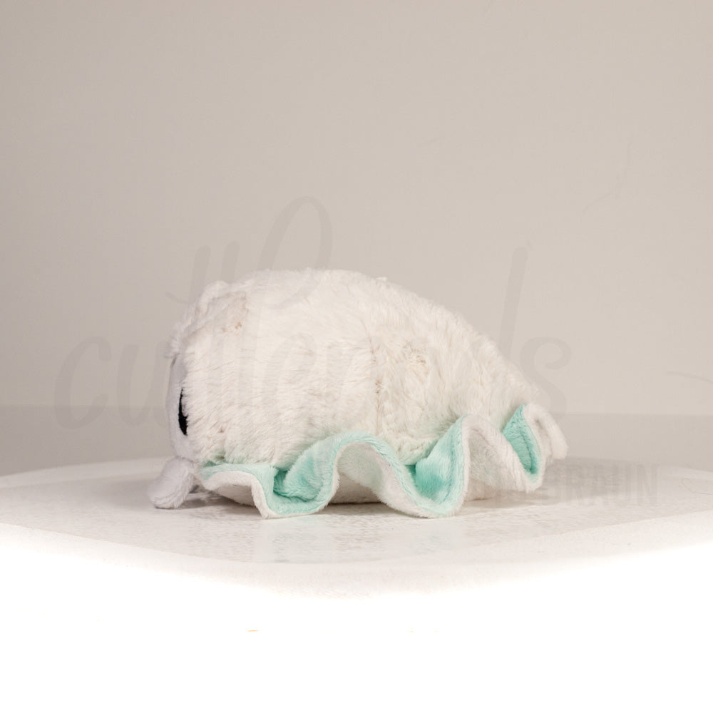 Side profile view of a cuttlepod plush toy, showcasing two-tone ruffled fins, and a cuddly, furry body.