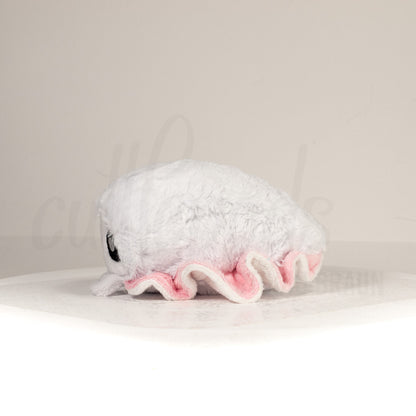 Side profile view of a cuttlepod plush toy, showcasing two-tone ruffled fins, and a cuddly, furry body.