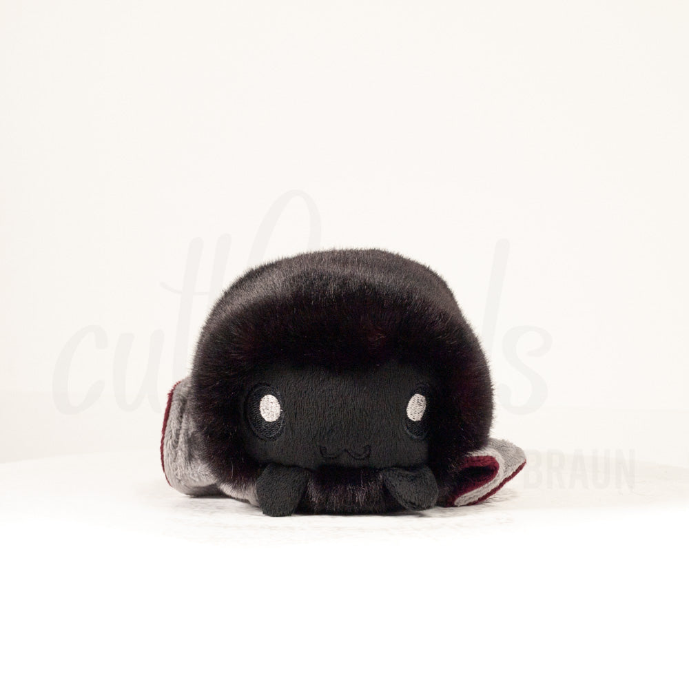 Front view of a cuttlepod plush toy, showcasing its unique form with large, cartoonish eyes, ruffled fins, and a cuddly, furry texture.