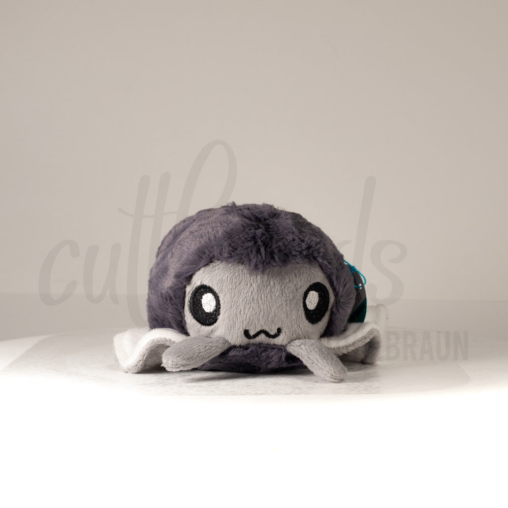 Front view of a cuttlepod plush toy, showcasing its unique form with large, cartoonish eyes, ruffled fins, and a cuddly, furry texture.