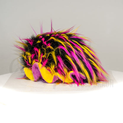 Slightly angled back view of a cuttlepod plush toy, highlighting two-tone ruffled fins, and a cuddly, furry body that comes to a soft point at the rear.