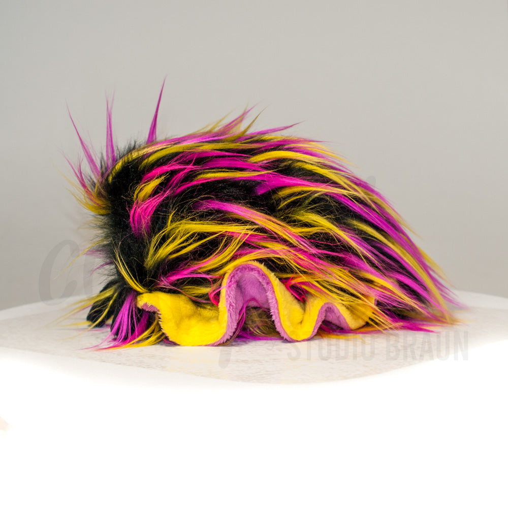 Side profile view of a cuttlepod plush toy, showcasing two-tone ruffled fins, and a cuddly, furry body.