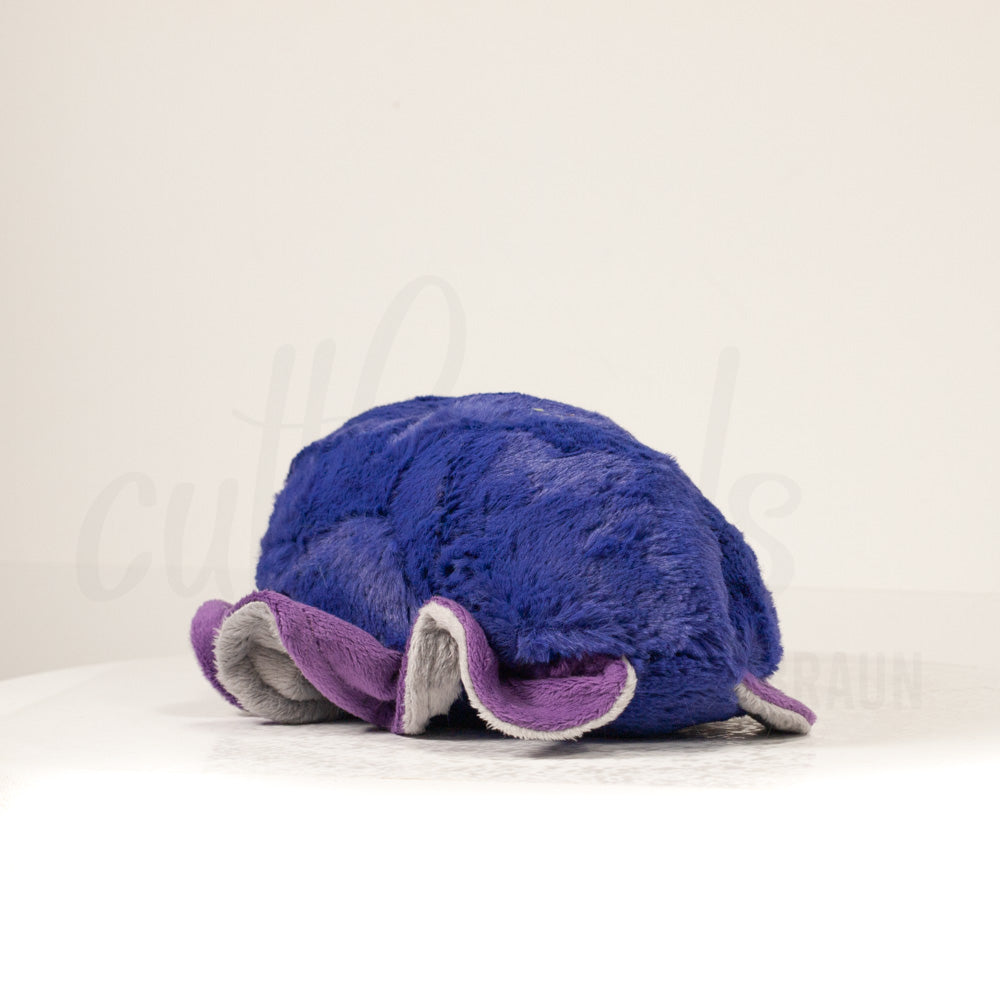 Slightly angled back view of a cuttlepod plush toy, highlighting two-tone ruffled fins, and a cuddly, furry body that comes to a soft point at the rear.