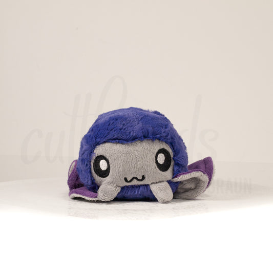 Front view of a cuttlepod plush toy, showcasing its unique form with large, cartoonish eyes, ruffled fins, and a cuddly, furry texture.