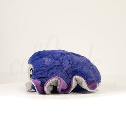 Side profile view of a cuttlepod plush toy, showcasing two-tone ruffled fins, and a cuddly, furry body.