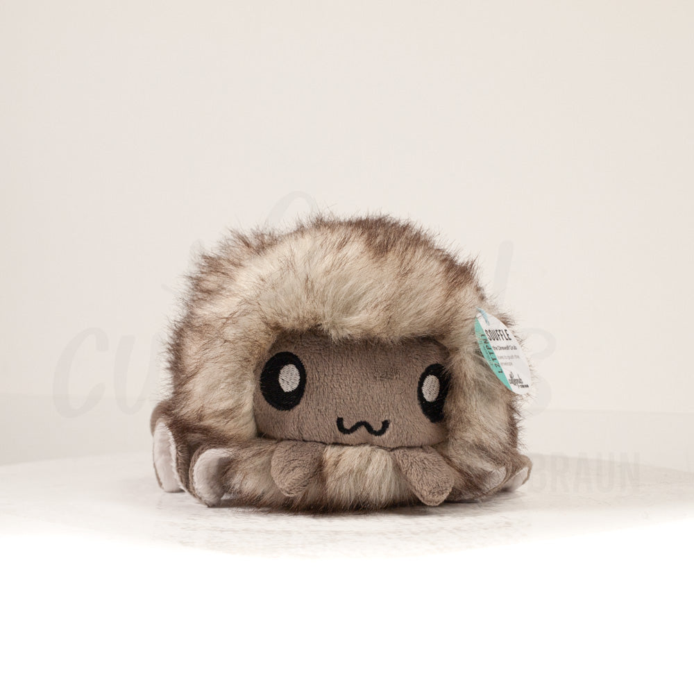 Front view of a cuttlepod plush toy, showcasing its unique form with large, cartoonish eyes, ruffled fins, and a cuddly, furry texture.