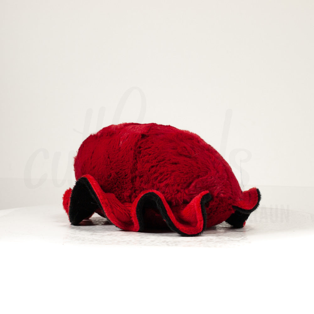 Slightly angled back view of a cuttlepod plush toy, highlighting two-tone ruffled fins, and a cuddly, furry body that comes to a soft point at the rear.