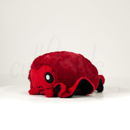 Front view of a cuttlepod plush toy, captured at a slight angle to highlight its charming features: large, cartoonish eyes, ruffled fins, and a cuddly, furry texture.