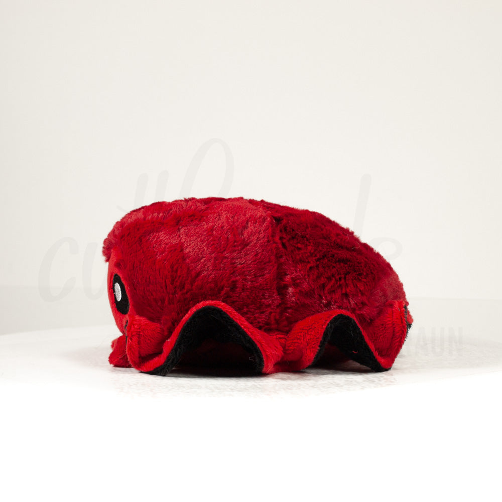 Side profile view of a cuttlepod plush toy, showcasing two-tone ruffled fins, and a cuddly, furry body.