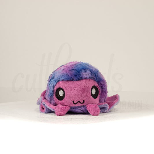 Front view of a cuttlepod plush toy, showcasing its unique form with large, cartoonish eyes, ruffled fins, and a cuddly, furry texture.