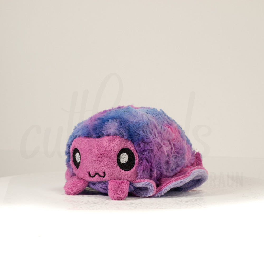 Front view of a cuttlepod plush toy, captured at a slight angle to highlight its charming features: large, cartoonish eyes, ruffled fins, and a cuddly, furry texture.