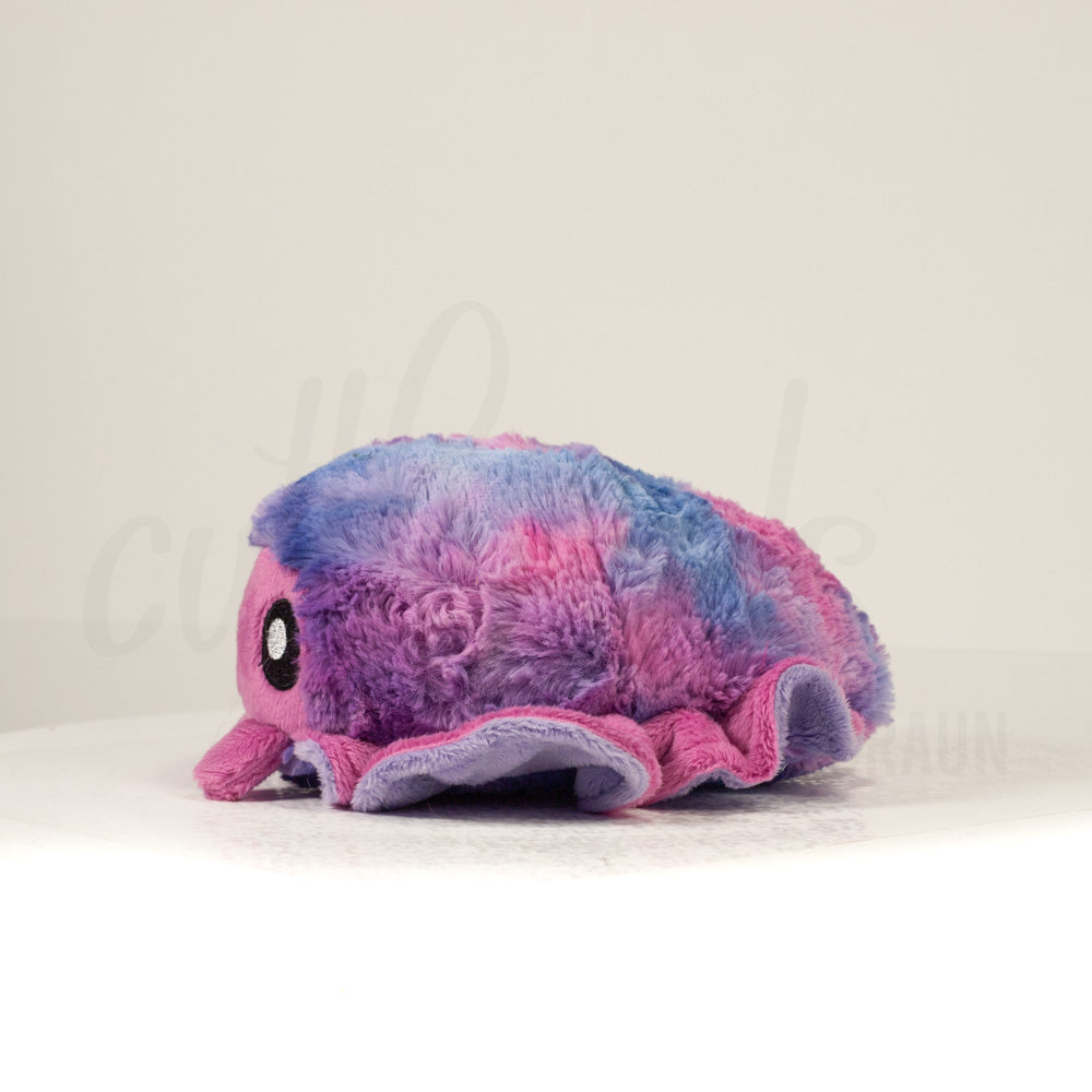 Side profile view of a cuttlepod plush toy, showcasing two-tone ruffled fins, and a cuddly, furry body.