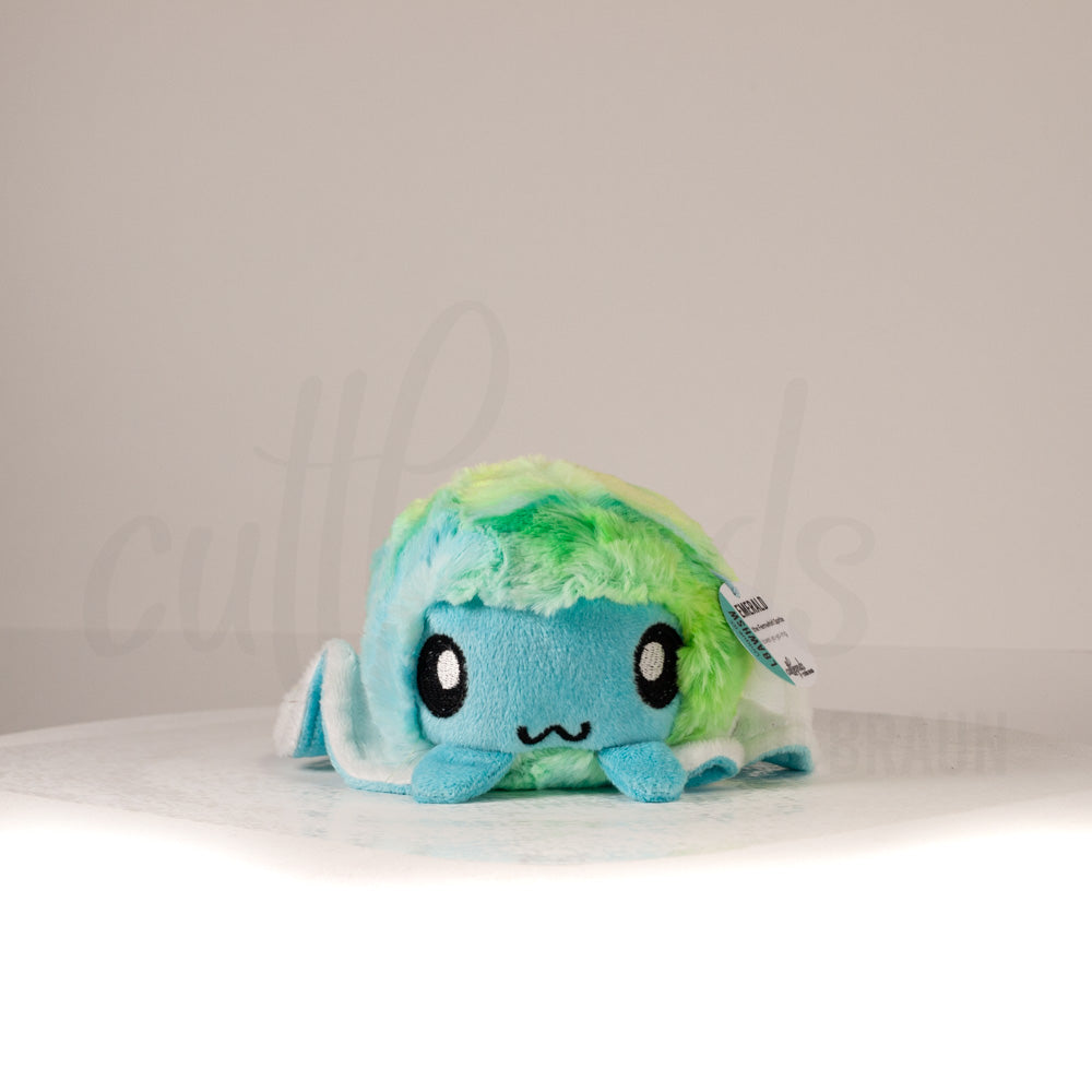 Front view of a cuttlepod plush toy, showcasing its unique form with large, cartoonish eyes, ruffled fins, and a cuddly, furry texture.