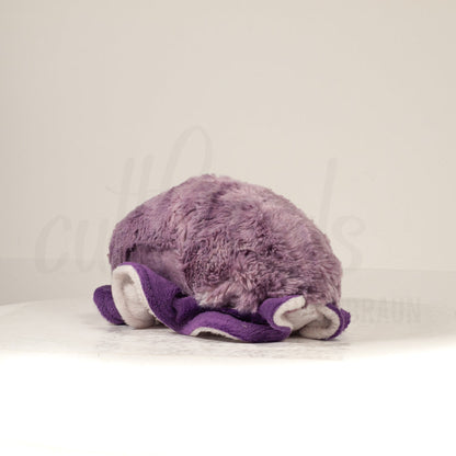 Slightly angled back view of a cuttlepod plush toy, highlighting two-tone ruffled fins, and a cuddly, furry body that comes to a soft point at the rear.