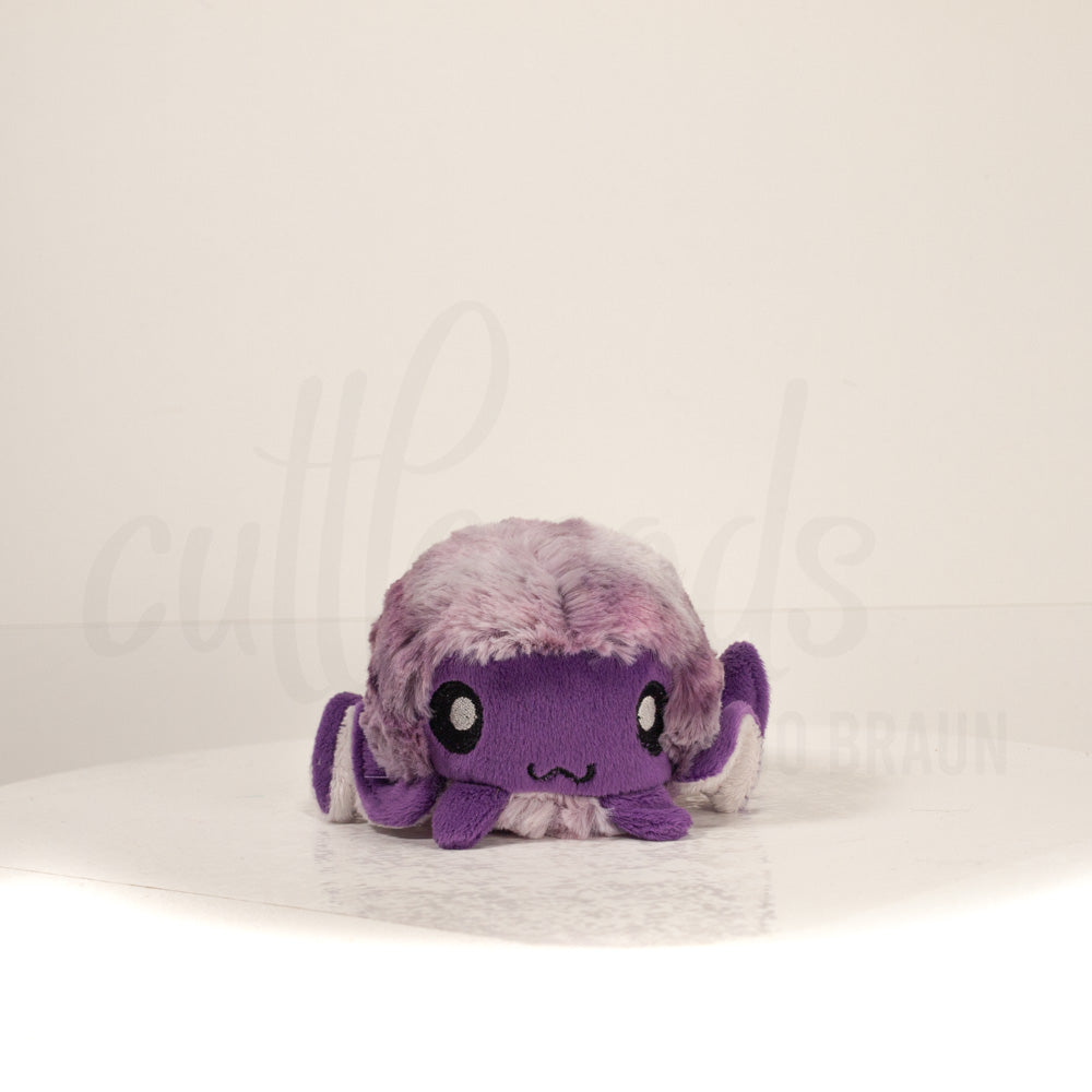 Front view of a cuttlepod plush toy, showcasing its unique form with large, cartoonish eyes, ruffled fins, and a cuddly, furry texture.