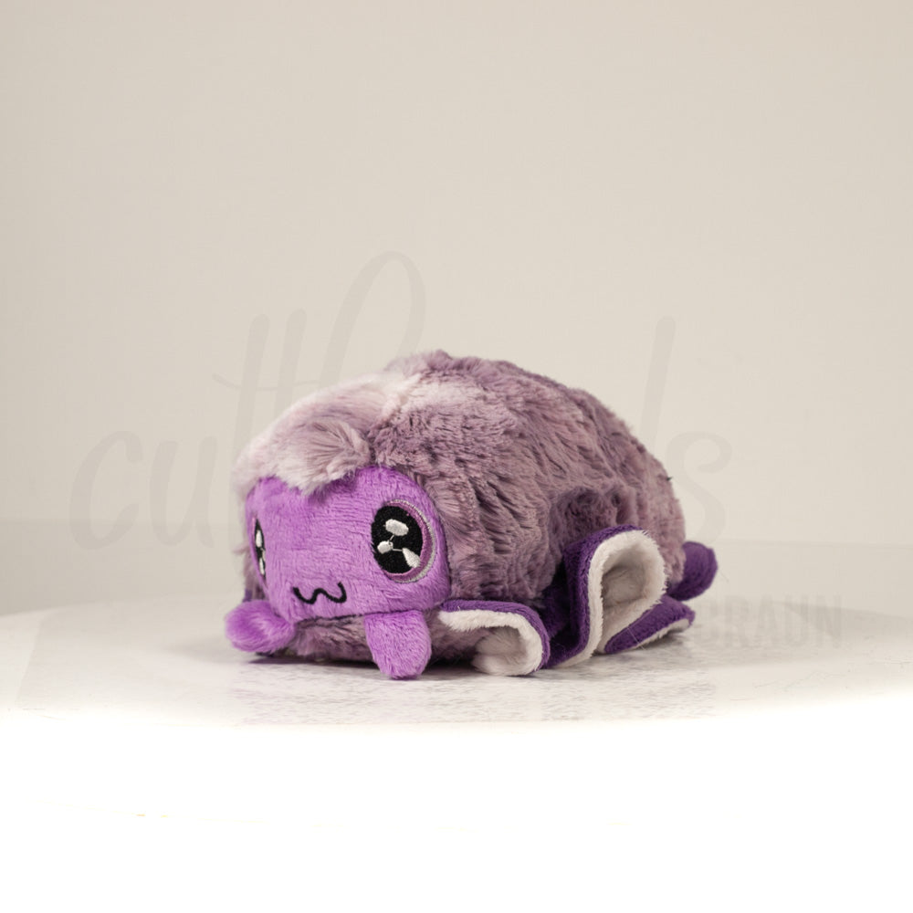 Front view of a cuttlepod plush toy, captured at a slight angle to highlight its charming features: large, cartoonish eyes, ruffled fins, and a cuddly, furry texture.