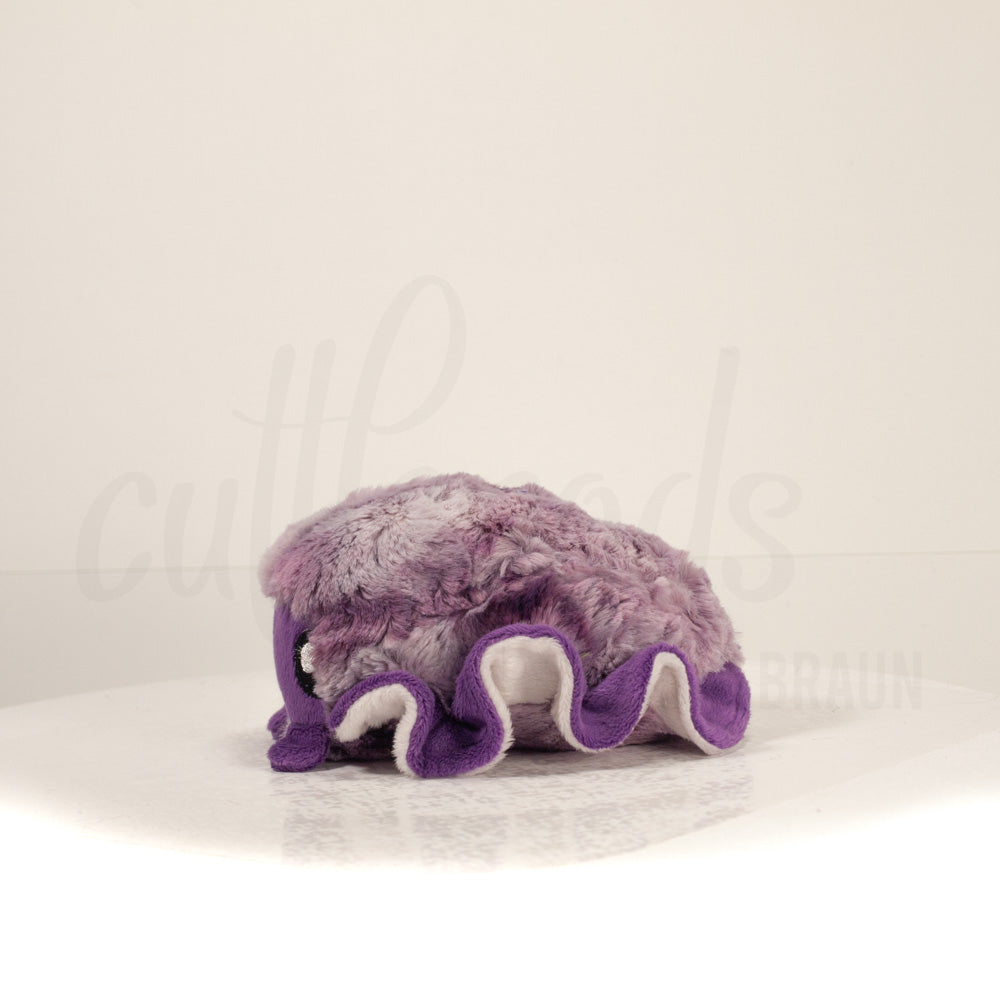 Side profile view of a cuttlepod plush toy, showcasing two-tone ruffled fins, and a cuddly, furry body.