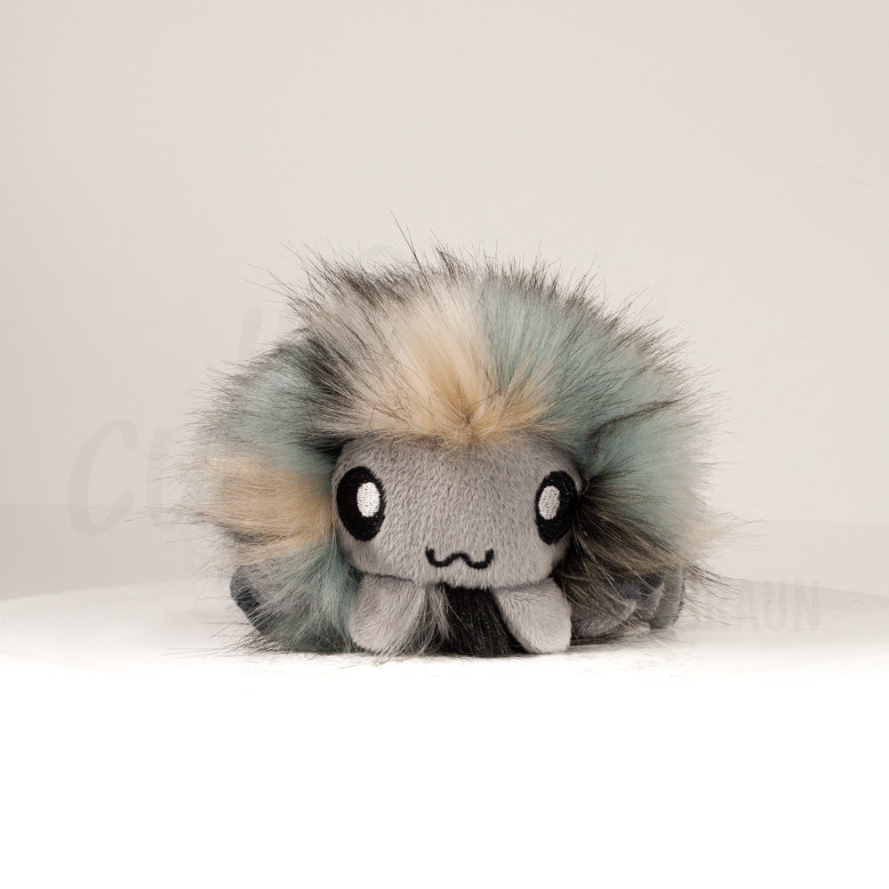 Front view of a cuttlepod plush toy, showcasing its unique form with large, cartoonish eyes, ruffled fins, and a cuddly, furry texture.